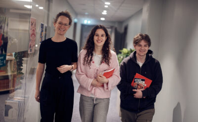 En lärare och två elever som går i skolans korridor.