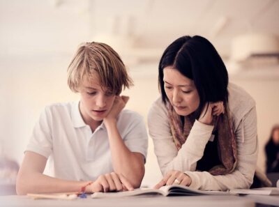 En lärare och elev på Snitz Grundskola läser tillsammans i en lärobok.