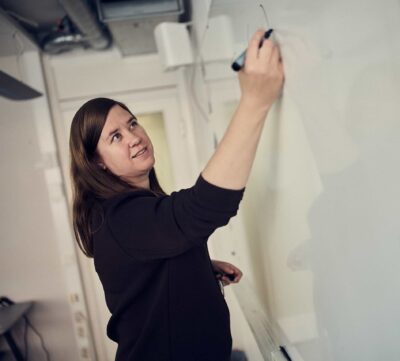 En lärare på Snitz Grundskola skriver på en whiteboard tavla i ett klassrum.