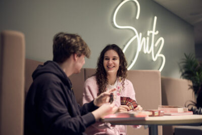 Två elever spelar Uno tillsammans i skolans soffor.