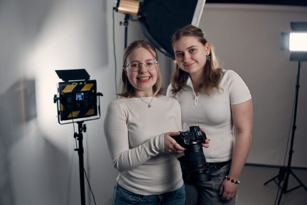 Två elever i fotostudio som med en kamera.