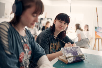 Elever i klassrum som målar med penslar.