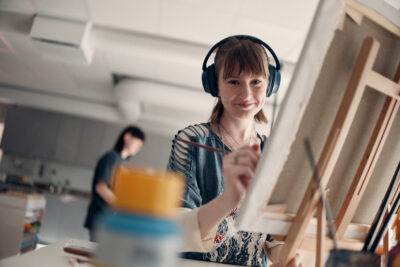 Glad elev med hörlurar som målar en tavla.