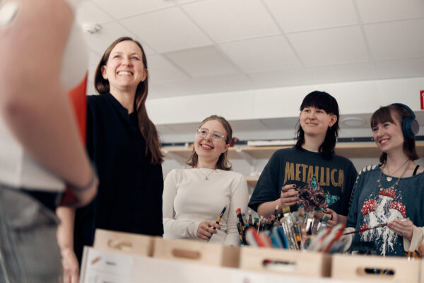 Glada elever och lärare framför penslar.