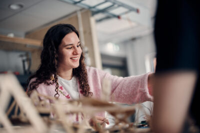 Glad elev i rosa kofta som arbetar med sitt projekt.