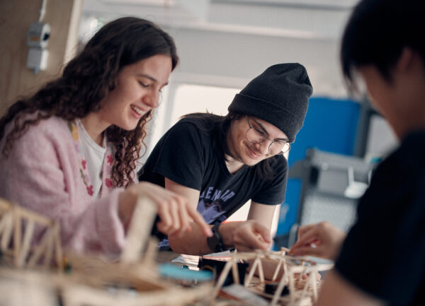 Tre glada elever som bygger på sina projekt.