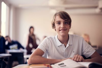 En elev på Snitz Grundskola sitter i ett klassrum med en lärobok framför sig.