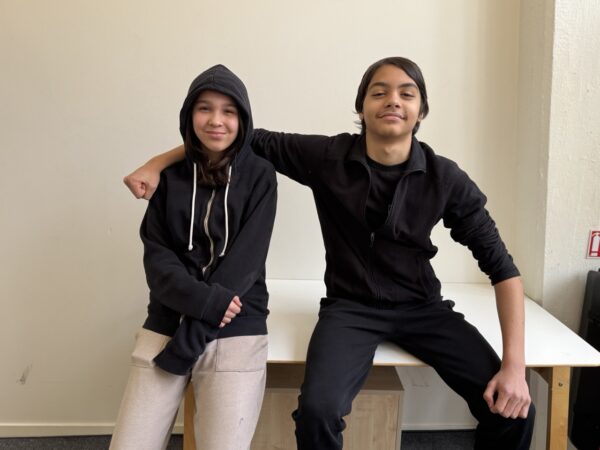 två elever håller om varandra och kollar in i kameran.